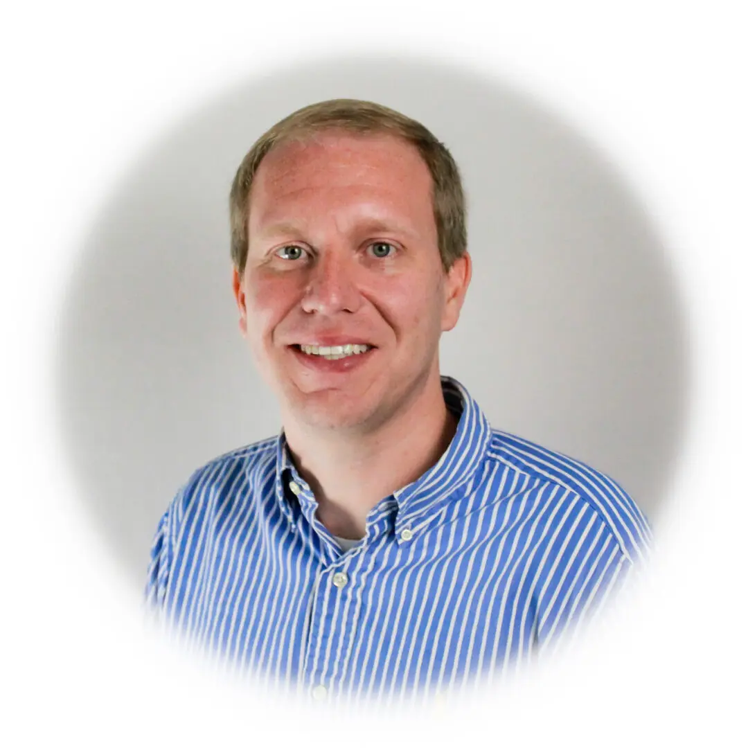 A man in blue and white striped shirt smiling.